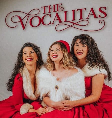 3 women in red Christmas outfits. The Vocalitas